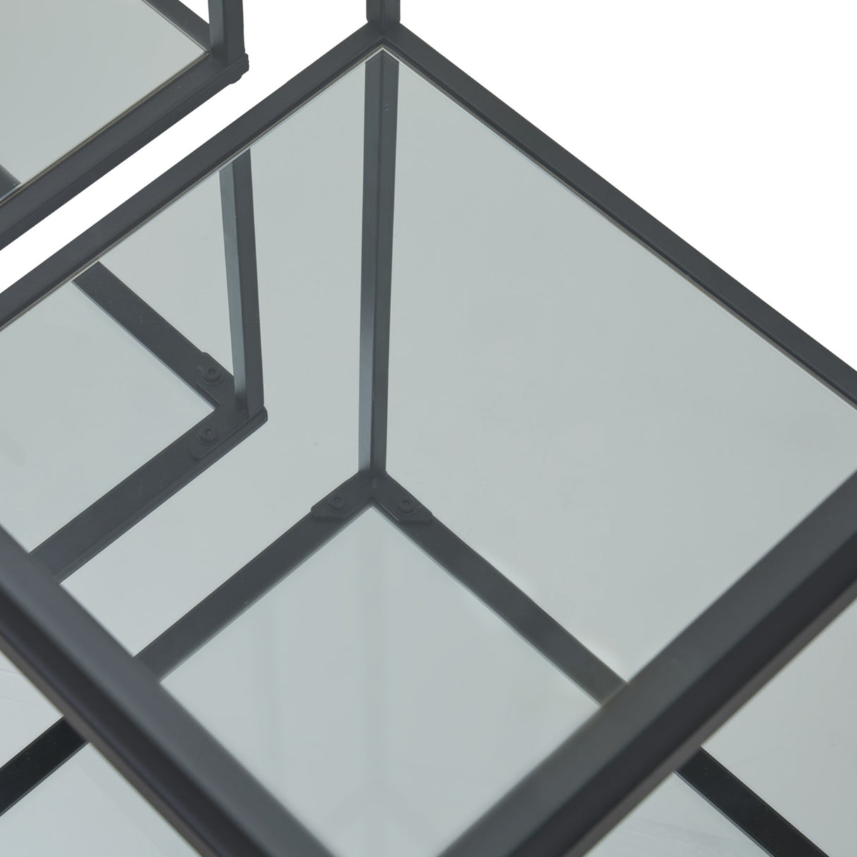 Close-up of the Hill Interiors Harweld side tables showing slim black metal frames and clear glass tops meeting at the corners.