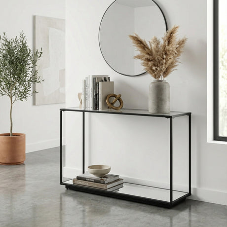 Hill Interiors Harweld console table with slim matte black metal frame and clear glass top, styled with books, vase and pampas in a bright hallway.