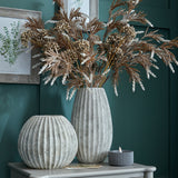 Hill Interiors Round Ceramic Vase in grey with ribbed textured finish, styled with dried foliage stems beside a smaller round vase on a console.