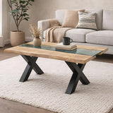 Hill Interiors Live Edge Acacia River coffee table with brown wood top, glass inlay and black metal X-base, styled in a neutral living room.