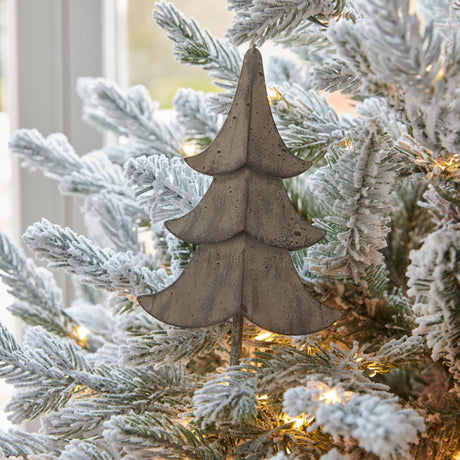 Hill Interiors Large Rustic Metal Hanging Tree in brown, a tiered fir silhouette with matte weathered finish, displayed on a flocked Christmas tree by a window.