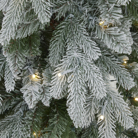 Close-up of Hill Interiors Slim Snowy Woodland Christmas tree branches with snow-dusted plastic needles and warm white LEDs woven through the foliage.