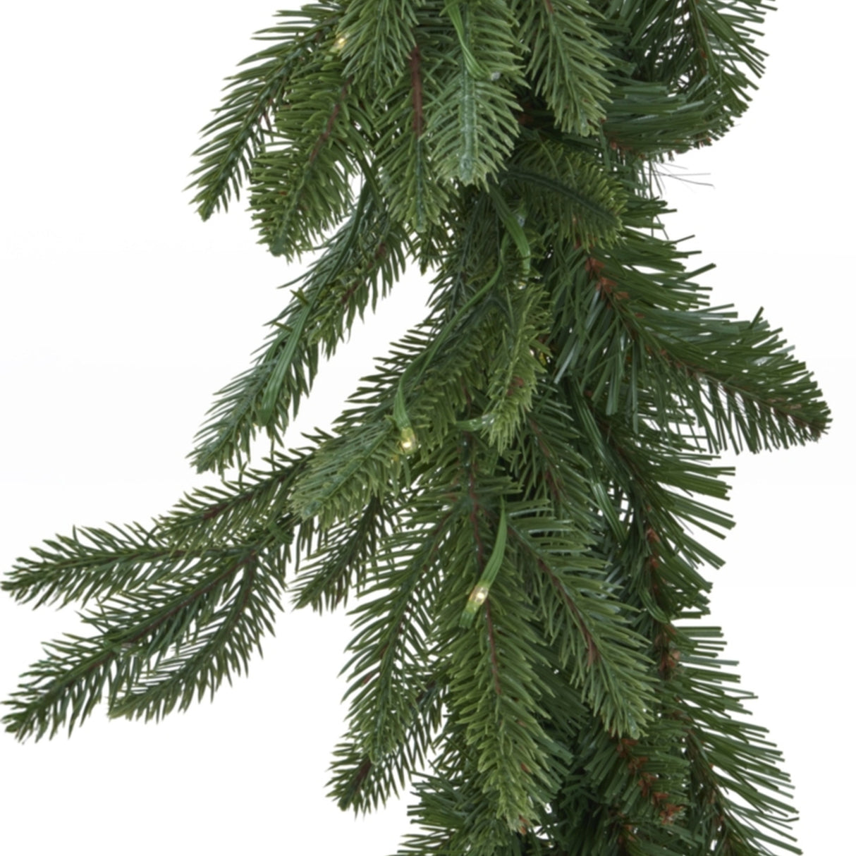Close-up of Hill Interiors Pre-Lit Woodland Fir Christmas Garland in green, showing dense plastic needles and small warm LED lights on a white background.