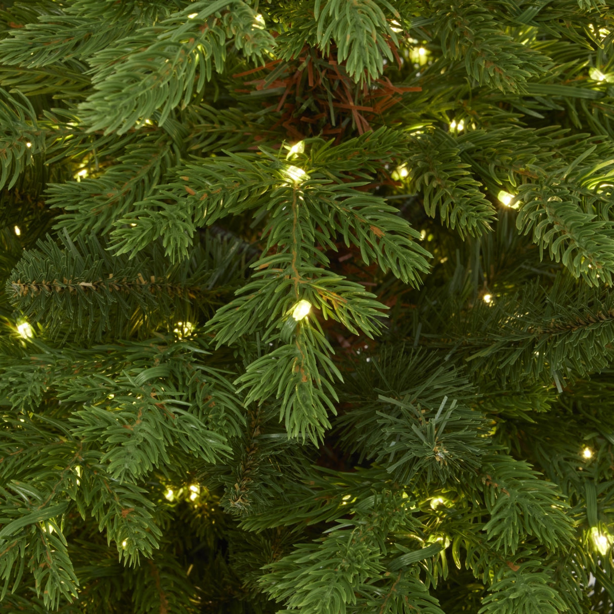 Close-up of Hill Interiors pre-lit fir Christmas tree showing green moulded plastic needles with warm white LED lights woven through the layered branches.