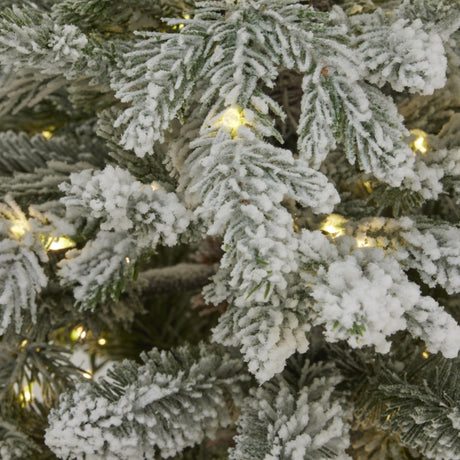 Close-up of Hill Interiors Snowy Forest Fir pre-lit Christmas tree showing frosted green plastic branches interwoven with warm white LED lights.