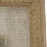 Close-up of the Hill Interiors Avocet on Linen framed wall art, showing the warm brown beaded wood frame corner and natural linen backing behind glass.