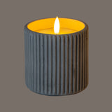 Hill Interiors Ribbed LED Pillar Candle in beige wax with vertical ribbed texture and glowing flame-effect light, shown against a grey background.
