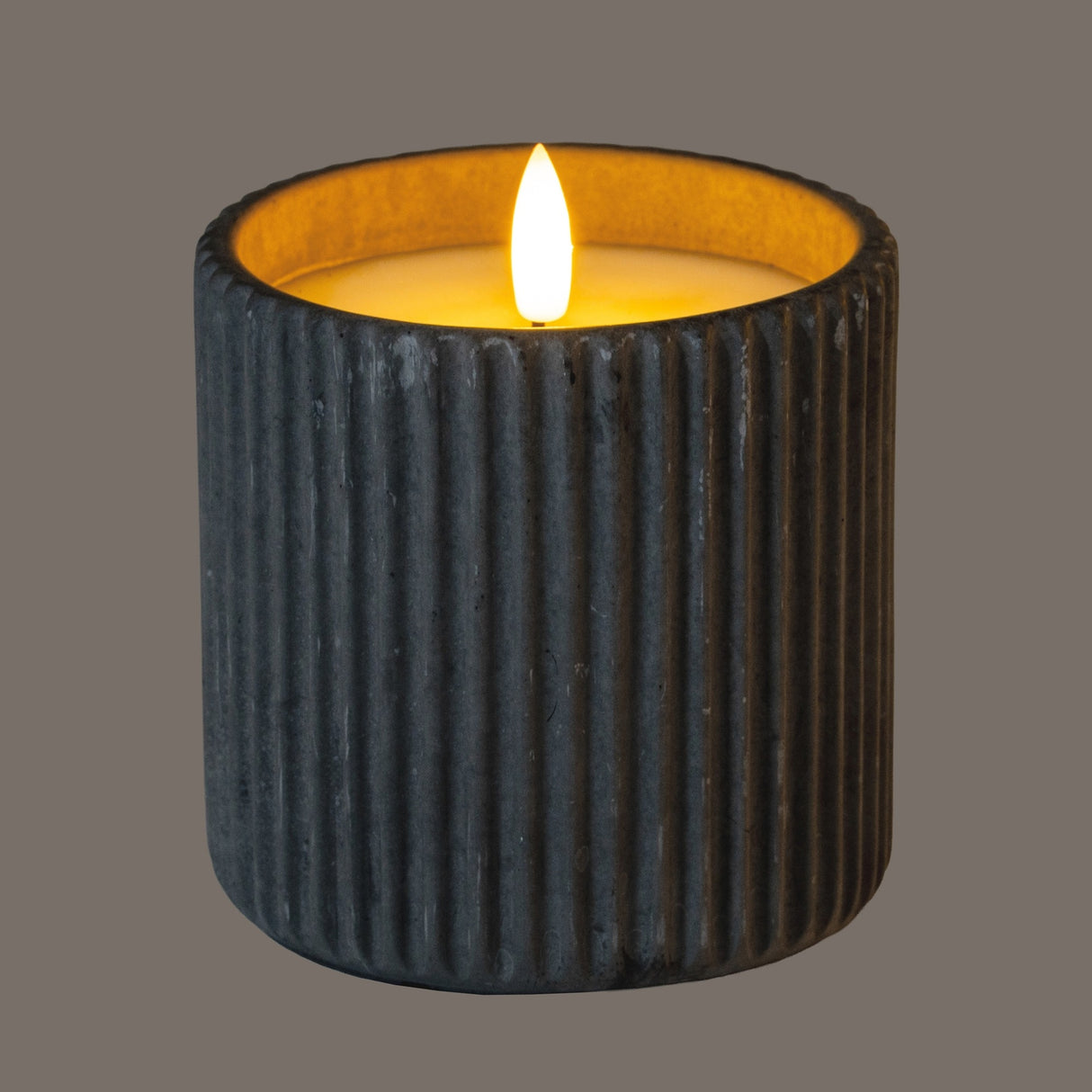 Hill Interiors Ribbed LED Pillar Candle in beige wax with vertical ribbing and a flickering flame effect, shown on a grey background.