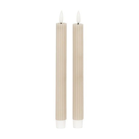 Pair of Hill Interiors Ribbed Taper Candles in beige wax with vertical fluting and slim upright form, shown on a plain white background.