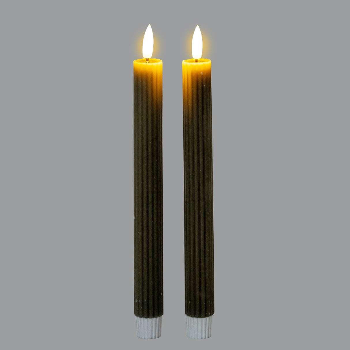 Pair of Hill Interiors Ribbed Taper Candles in beige wax with fine vertical ribbing and lit flames, shown upright against a plain grey background.