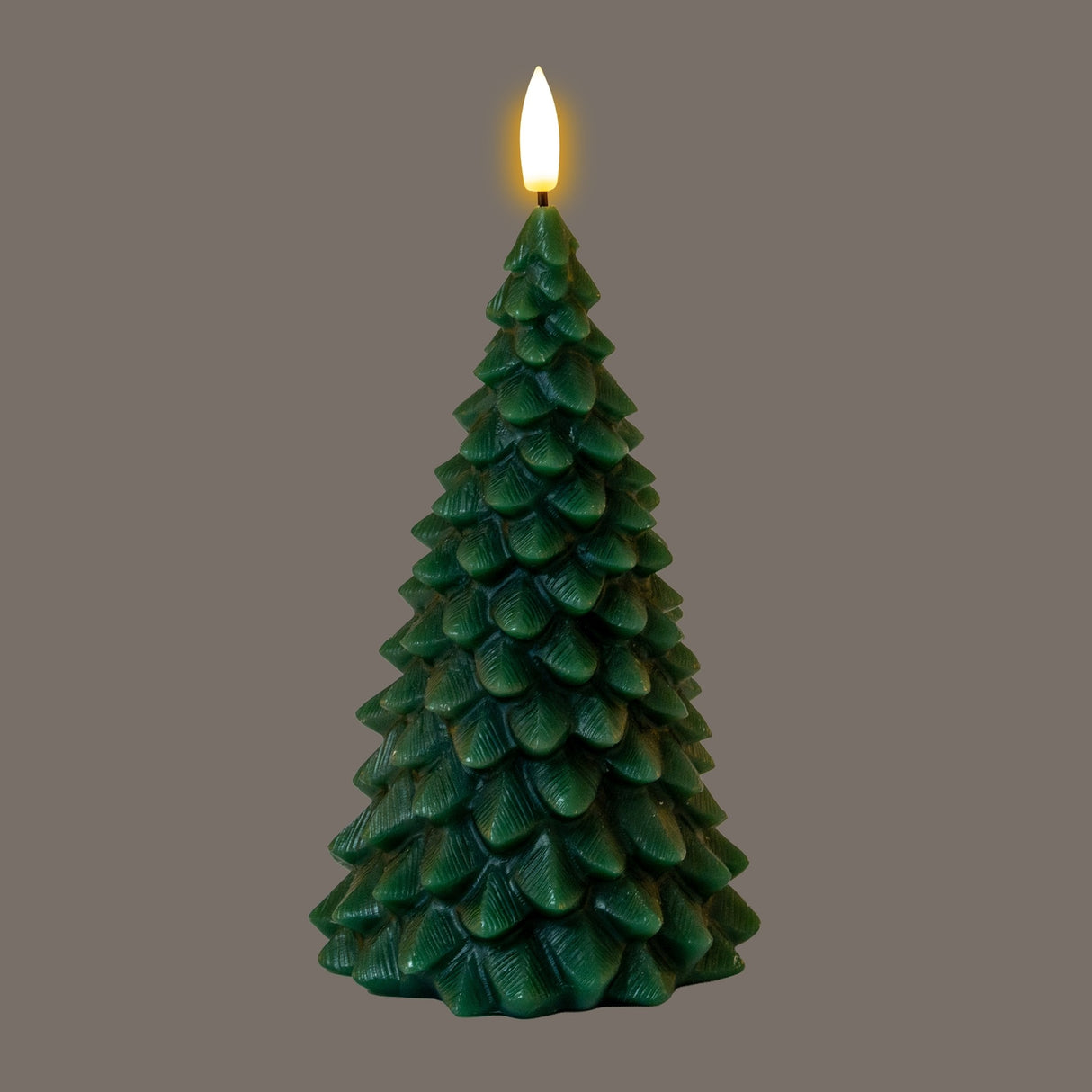 Hill Interiors Natural Glow Green Tree LED wax candle shaped as a layered pine tree with a warm flickering LED flame at the top, on a grey background.