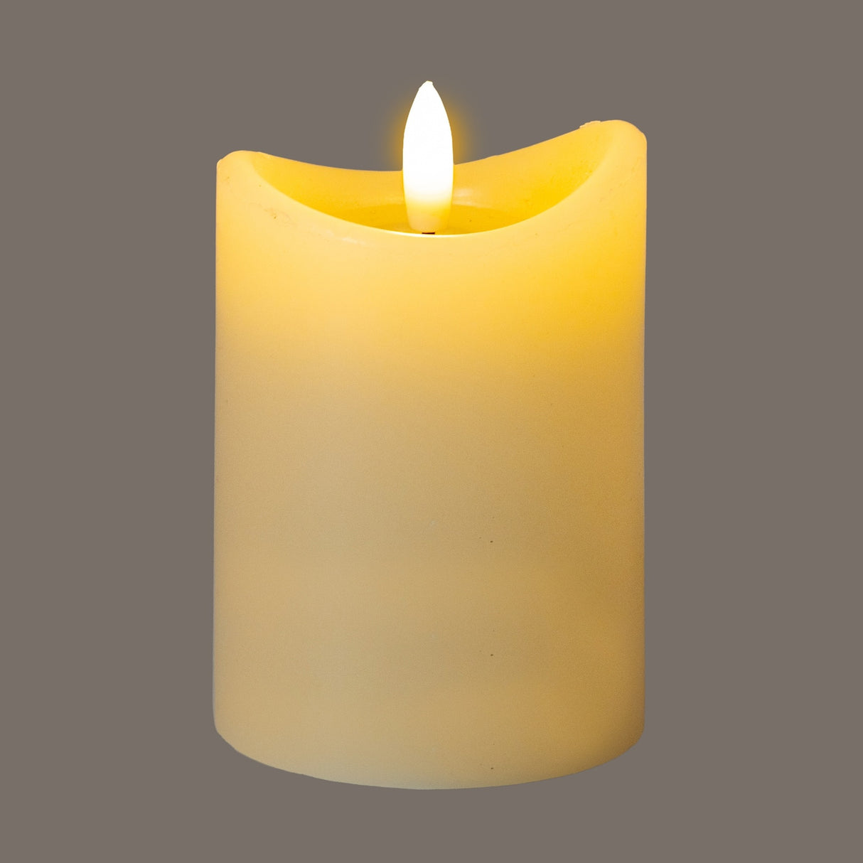 Hill Interiors Natural Glow LED pillar candle in beige plastic with a melted-effect top and flickering flame, shown against a grey background.