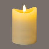 Hill Interiors Natural Glow LED pillar candle in beige plastic with a melted-effect top and flickering flame, shown against a grey background.