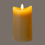 Hill Interiors Natural Glow beige LED pillar candle with melted-edge top and flickering flame, shown against a plain grey background.