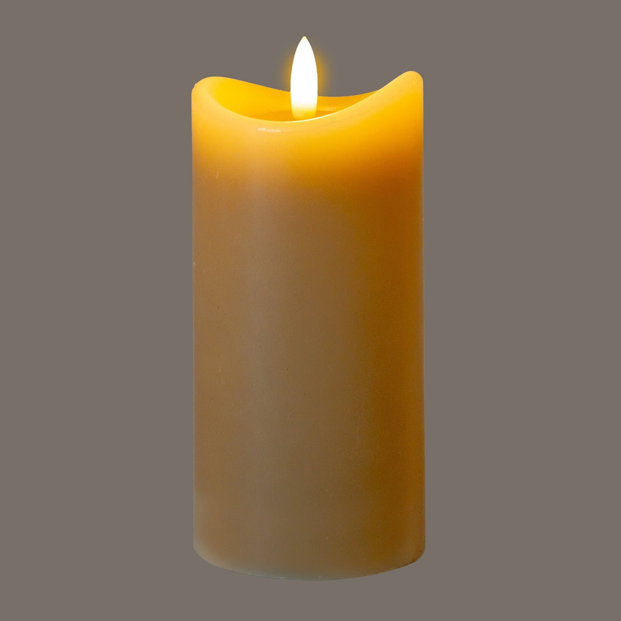 Hill Interiors Natural Glow beige LED pillar candle with wax-effect melted top and flickering flame, shown against a grey background.