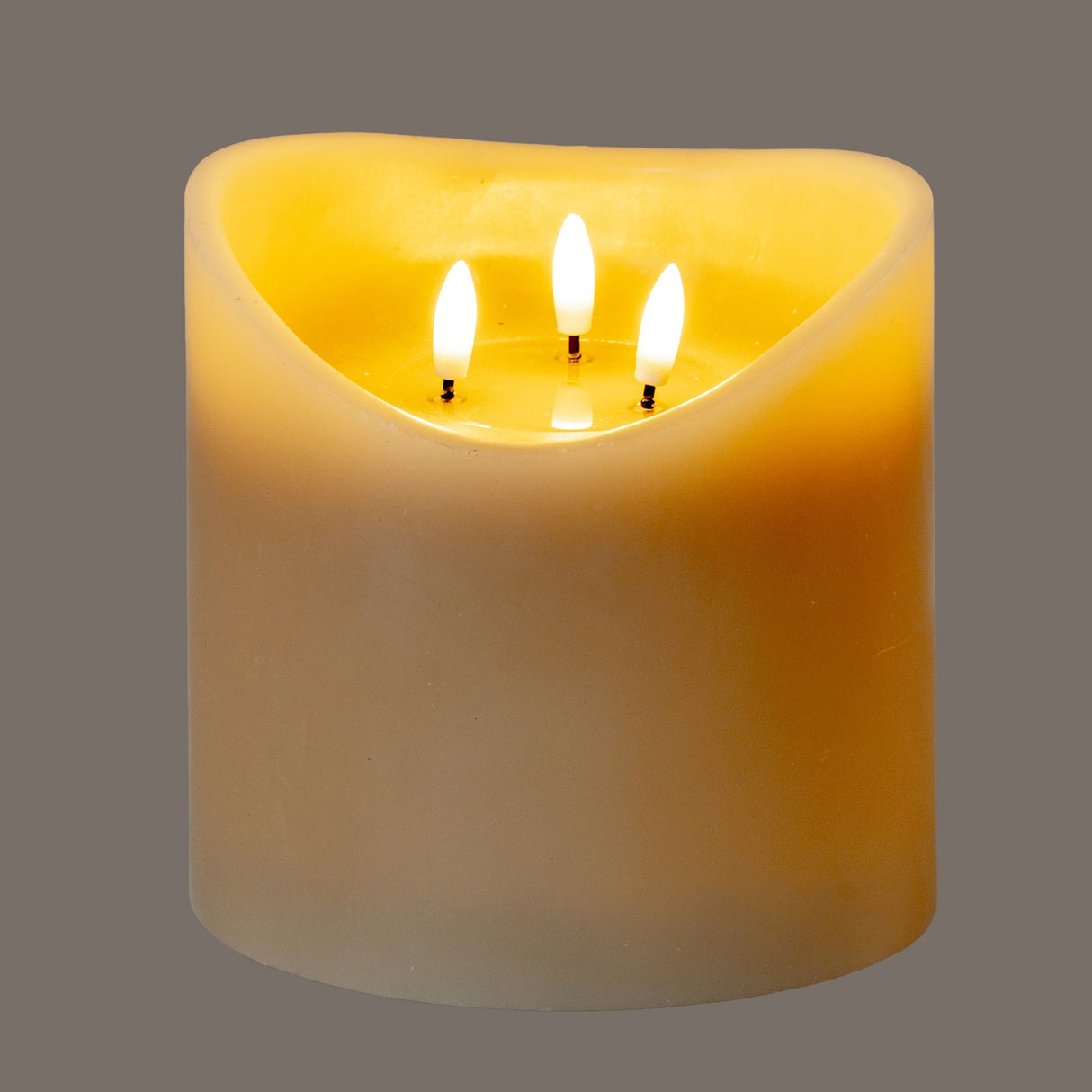 Hill Interiors Natural Glow beige LED pillar candle with melted top and three flickering flame-effect lights, shown on a plain grey background.