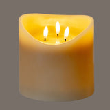 Hill Interiors Natural Glow beige LED pillar candle with melted top and three flickering flame-effect lights, shown on a plain grey background.