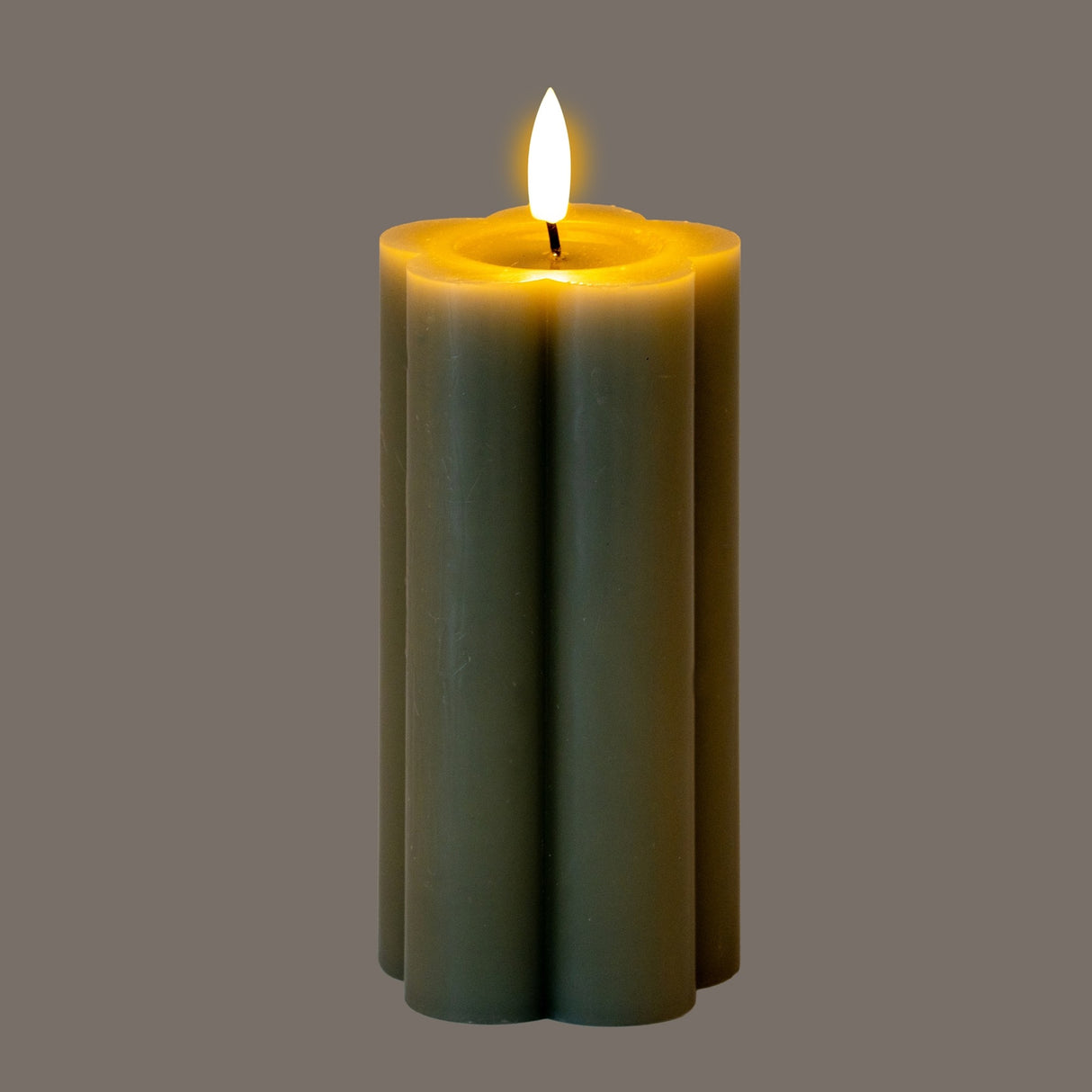 Hill Interiors Natural Glow LED pillar candle in beige plastic with a scalloped fluted shape and flickering flame effect, shown on a grey background.