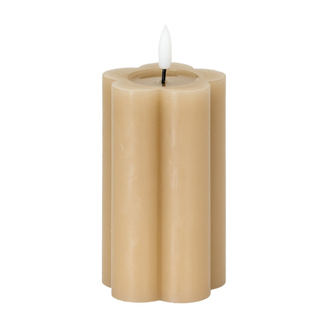 Hill Interiors Natural Glow Stone LED pillar candle in beige with a scalloped flower-shaped body and white flickering LED flame, on a white background.
