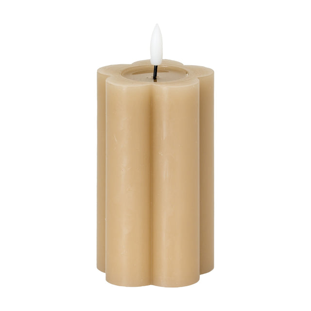 Hill Interiors Natural Glow Stone LED pillar candle in beige with a scalloped flower-shaped body and white flickering LED flame, on a white background.