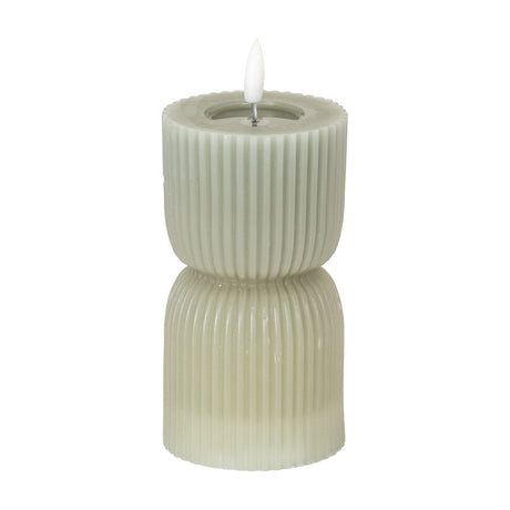 Hill Interiors Natural Glow carved LED pillar candle in beige with ribbed hourglass shape and flickering faux flame, shown on a plain white background.