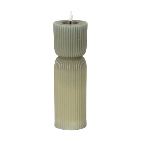 Hill Interiors Natural Glow carved LED pillar candle in beige, with ribbed plastic surface and flickering flame-shaped tip, shown on a white background.
