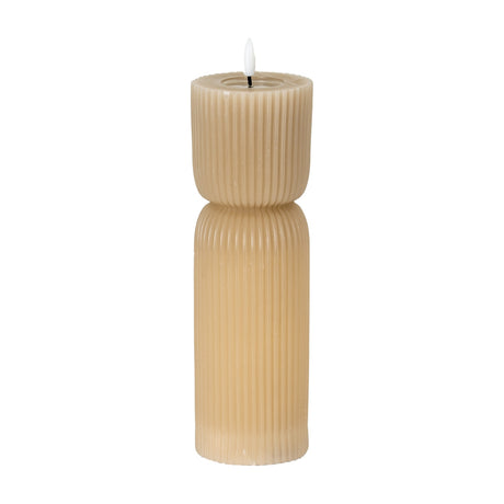 Hill Interiors Natural Glow beige stone-carved LED pillar candle with ribbed hourglass form and soft flickering flame tip, shown on a plain white background.