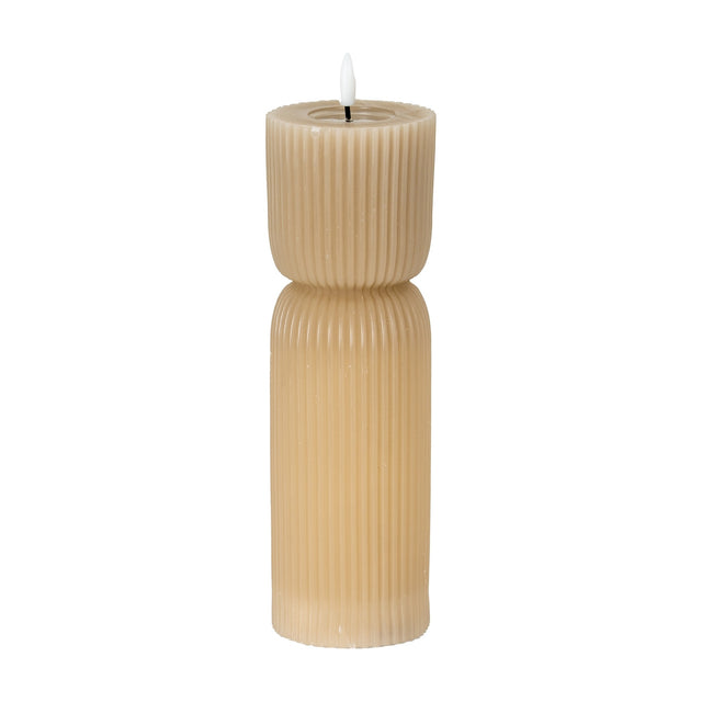 Hill Interiors Natural Glow beige stone-carved LED pillar candle with ribbed hourglass form and soft flickering flame tip, shown on a plain white background.