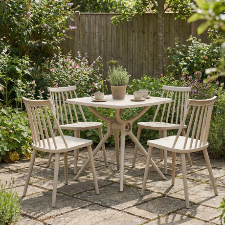 Hill Interiors Brolvanic Accent Chairs in beige plastic with spindle backs, set of four around a matching table on a garden patio.