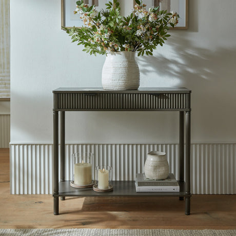 Hill Interiors 2 Drawer Wooden Console Table in brown with fluted drawer fronts and lower shelf, styled with a floral vase, candles and books in a hallway.