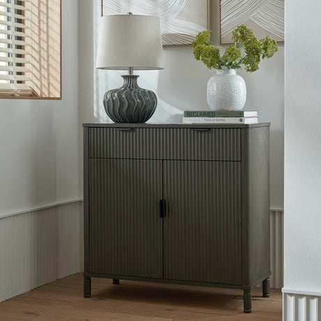 Hill Interiors Wooden Ribbed Two-Door Cabinet in brown with single drawer, styled with a lamp, vase and books in a bright hallway corner.