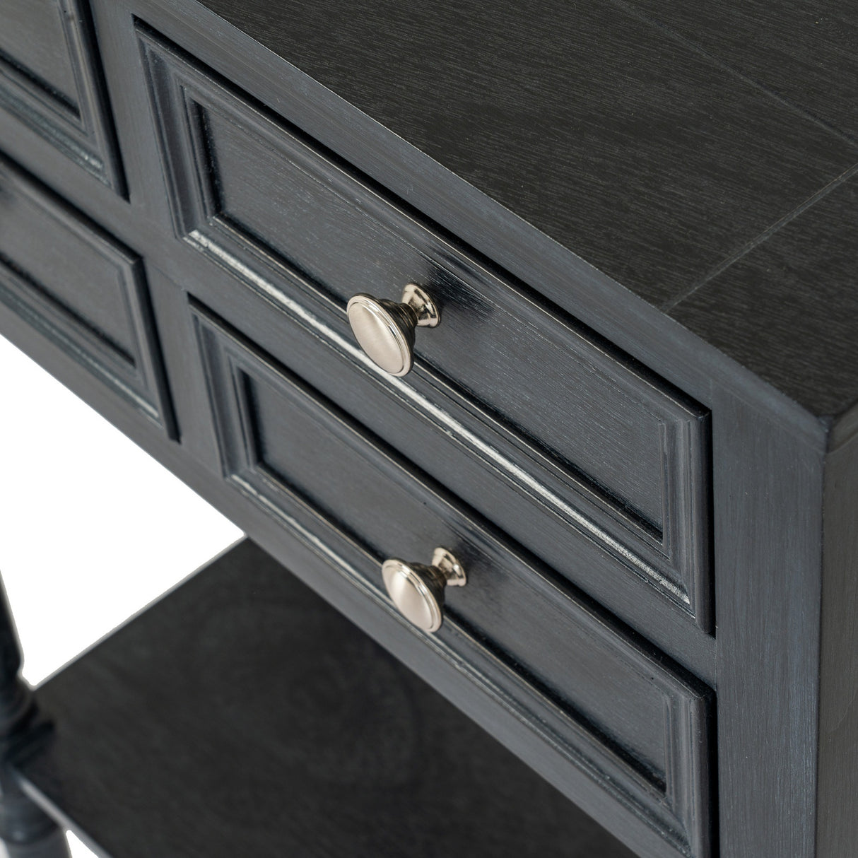 Close-up of the Hill Interiors 4 Drawer Side Table in black wood, showing panelled drawer fronts with round brushed metal knobs and a lower shelf.