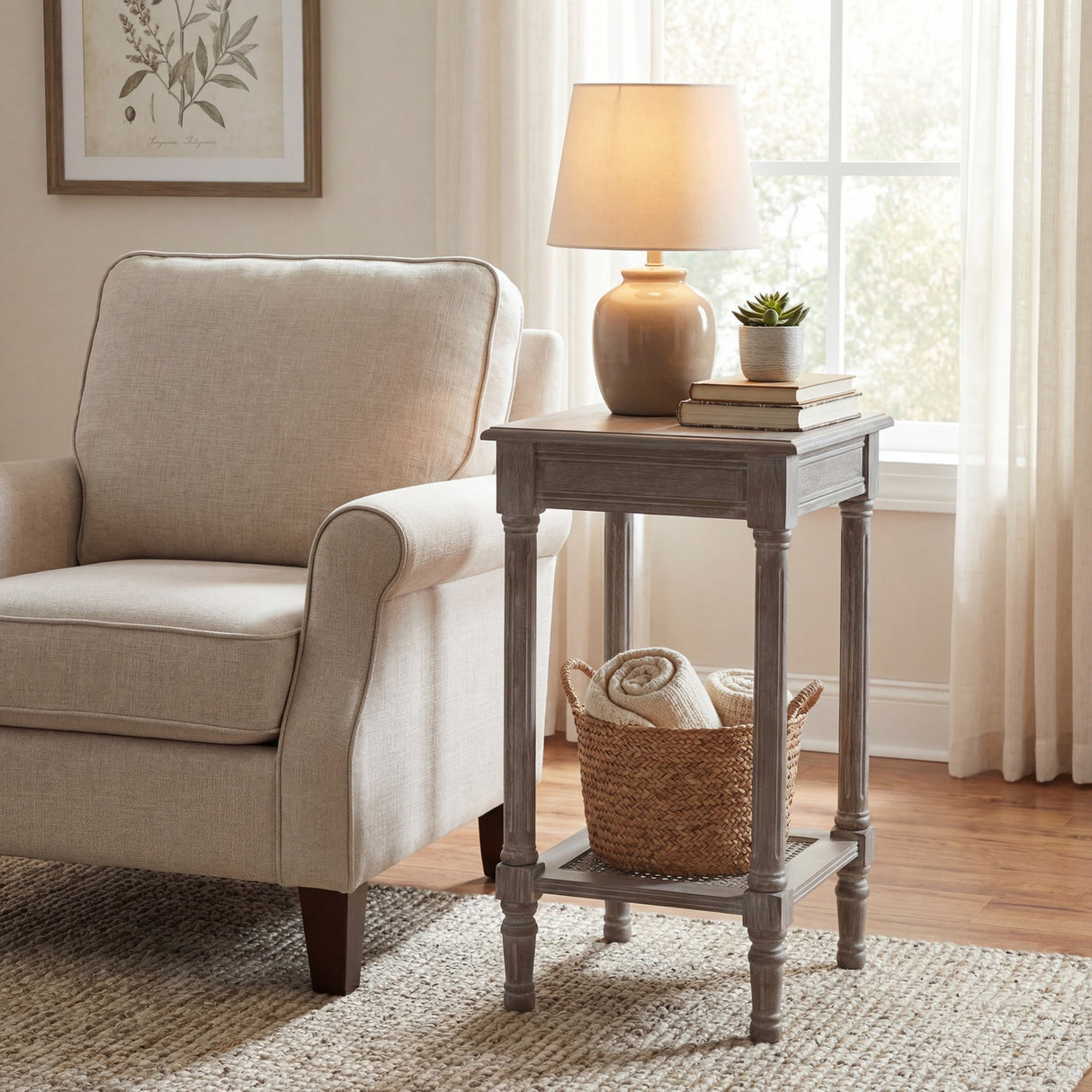 Hill Interiors Small Rattan Side Table in grey wash beside a cream armchair, styled with a lamp, books, succulent and woven basket on the lower shelf.