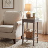 Hill Interiors Small Rattan Side Table in grey wash beside a cream armchair, styled with a lamp, books, succulent and woven basket on the lower shelf.