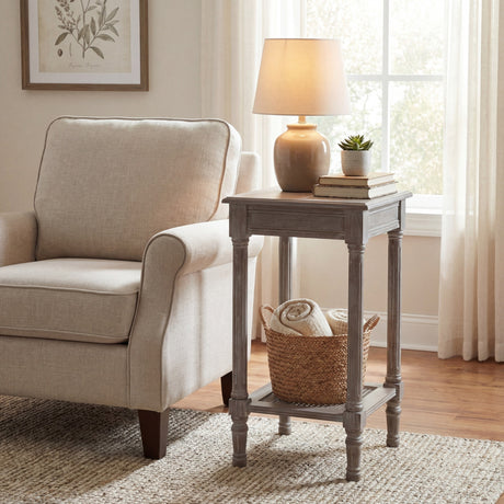 Hill Interiors Small Rattan Side Table in grey wash beside a cream armchair, styled with a lamp, books, succulent and woven basket on the lower shelf.