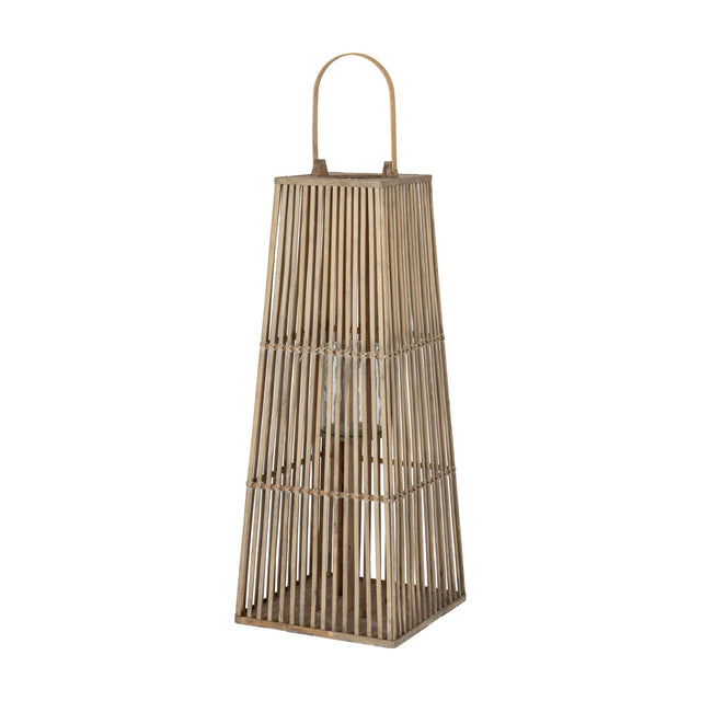 Hill Interiors large wicker lantern in warm brown with tapered slatted frame, arched handle and inner glass candle holder, on a plain white background.