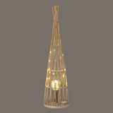 Hill Interiors large conical wicker lantern in brown with woven tapered frame, glass candle holder and lit LED fairy lights on a grey background.