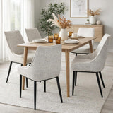 Hill Interiors Vaxeer dining chairs in white textured upholstery with black metal legs, arranged around an oak dining table in a neutral styled room.