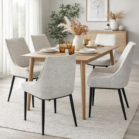 Hill Interiors Vaxeer dining chairs in white textured upholstery with black metal legs, arranged around an oak dining table in a neutral styled room.