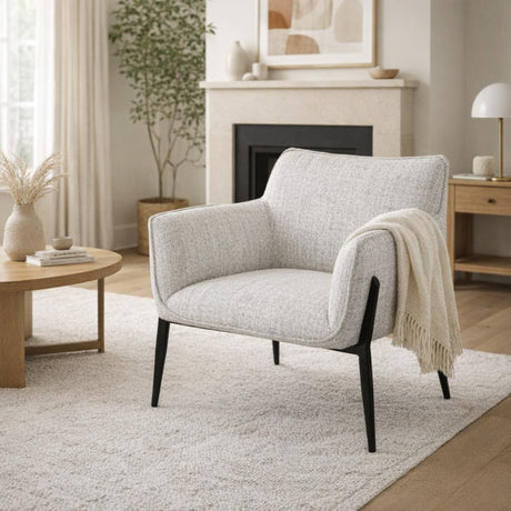 Hill Interiors Vaxeer accent chair with light grey textured upholstery and slim black metal legs, styled with a cream throw in a neutral living room.