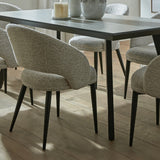 Hill Interiors Marlenza Curved Dining Chairs in neutral textured upholstery with black tapered legs, around a dark rectangular dining table on wood flooring.