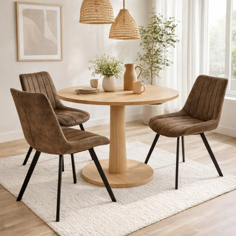 Hill Interiors Draxinby brown upholstered swivel dining chairs with black metal legs around a round oak pedestal table in a bright dining room.