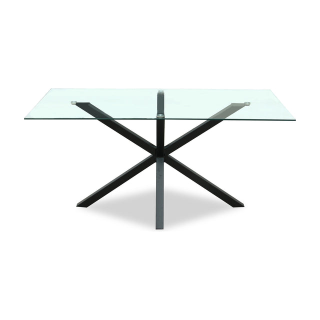 Hill Interiors Vestamby rectangular dining table with a clear tempered glass top on a black crossed metal base, shown on a plain white background.