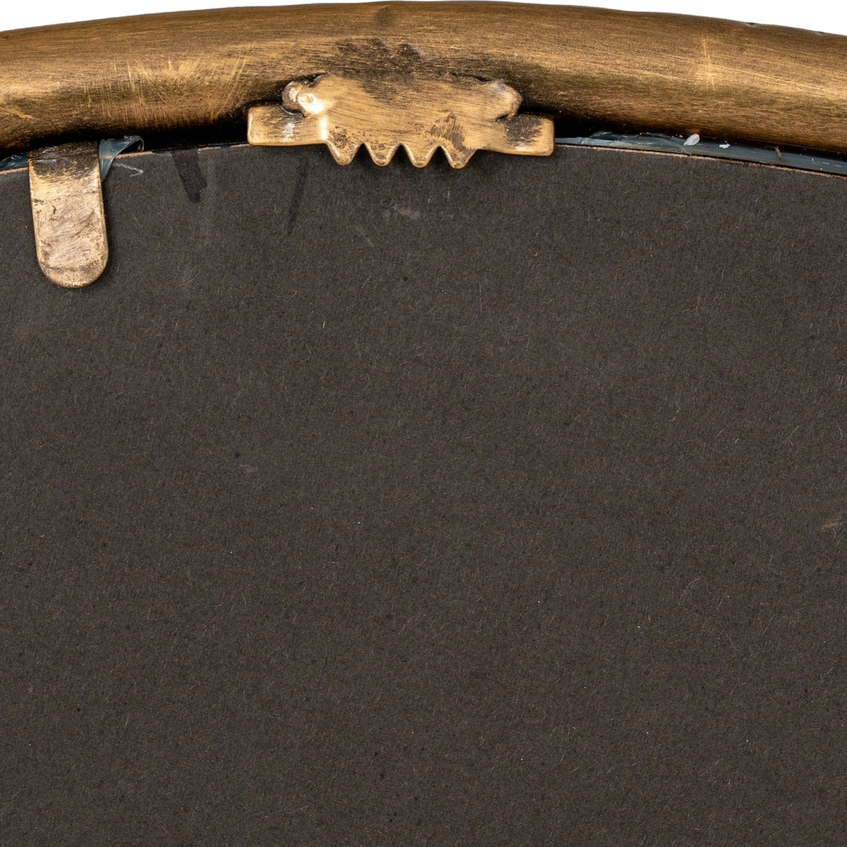 Close-up of the gold dimpled frame back on the Hill Interiors Sillura round wall mirror, showing sawtooth hanger and metal retaining clip.