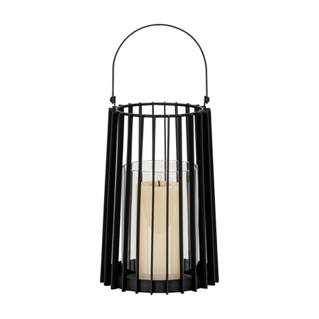 Hill Interiors medium black metal lantern with slatted frame, arched carry handle and clear glass holder with pillar candle, on a white background.