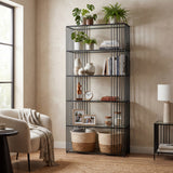 Hill Interiors glass shelf unit with slim black metal frame and five tempered glass shelves, styled with plants, books, vases and baskets in a living room.