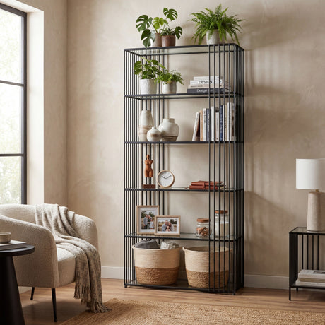 Hill Interiors glass shelf unit with slim black metal frame and five tempered glass shelves, styled with plants, books, vases and baskets in a living room.