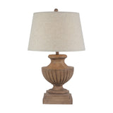 Hill Interiors table lamp with sculpted brown resin urn base on a square plinth and edged cream linen tapered shade, on a plain background.