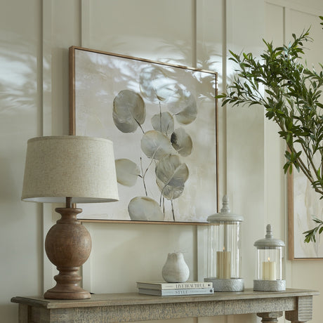Hill Interiors table lamp with sculpted brown resin base and edged linen shade, styled on a console with botanical artwork, candle lanterns, and olive foliage.