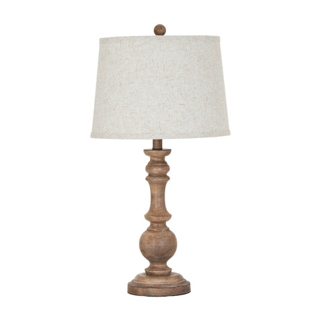 Hill Interiors Velantha table lamp with a sculptural brown resin candlestick base and tapered edged linen shade, shown on a plain white background.